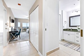 A modern hotel room with a balcony, a desk with a chair, a large mirror, and a bathroom with a sink and vanity. - Oceanview studio for 4 with balcony (Miramar Beach)