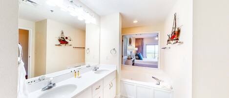 A bathroom with two sinks, a mirror, and a bathtub.