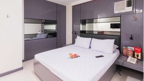 A modern bedroom with a large bed, a bedside telephone, and a mirror above the bed. - Hotel Sogo Baliwag Bulacan (Baliuag)