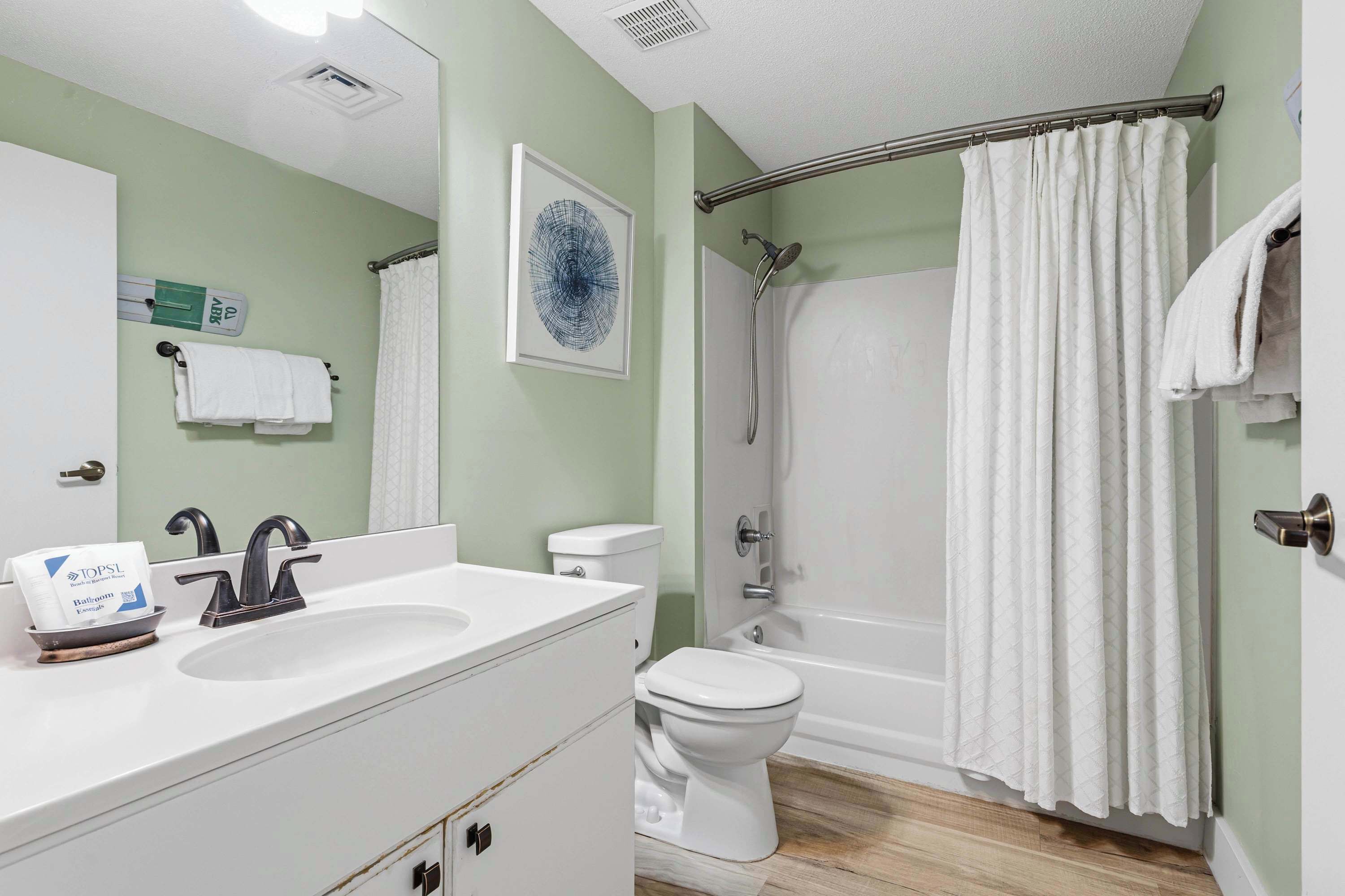 A bathroom with a double sink, toilet, shower, and a towel rack.