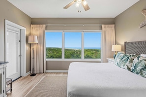 A bedroom with a large bed, a ceiling fan, a view of the outdoors, and a window with curtains. - Exclusive beachfront studio for 2 (Miramar Beach)