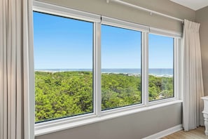A room with a large window offering a view of a forest and a beach. - Exclusive beachfront studio for 2 (Miramar Beach)