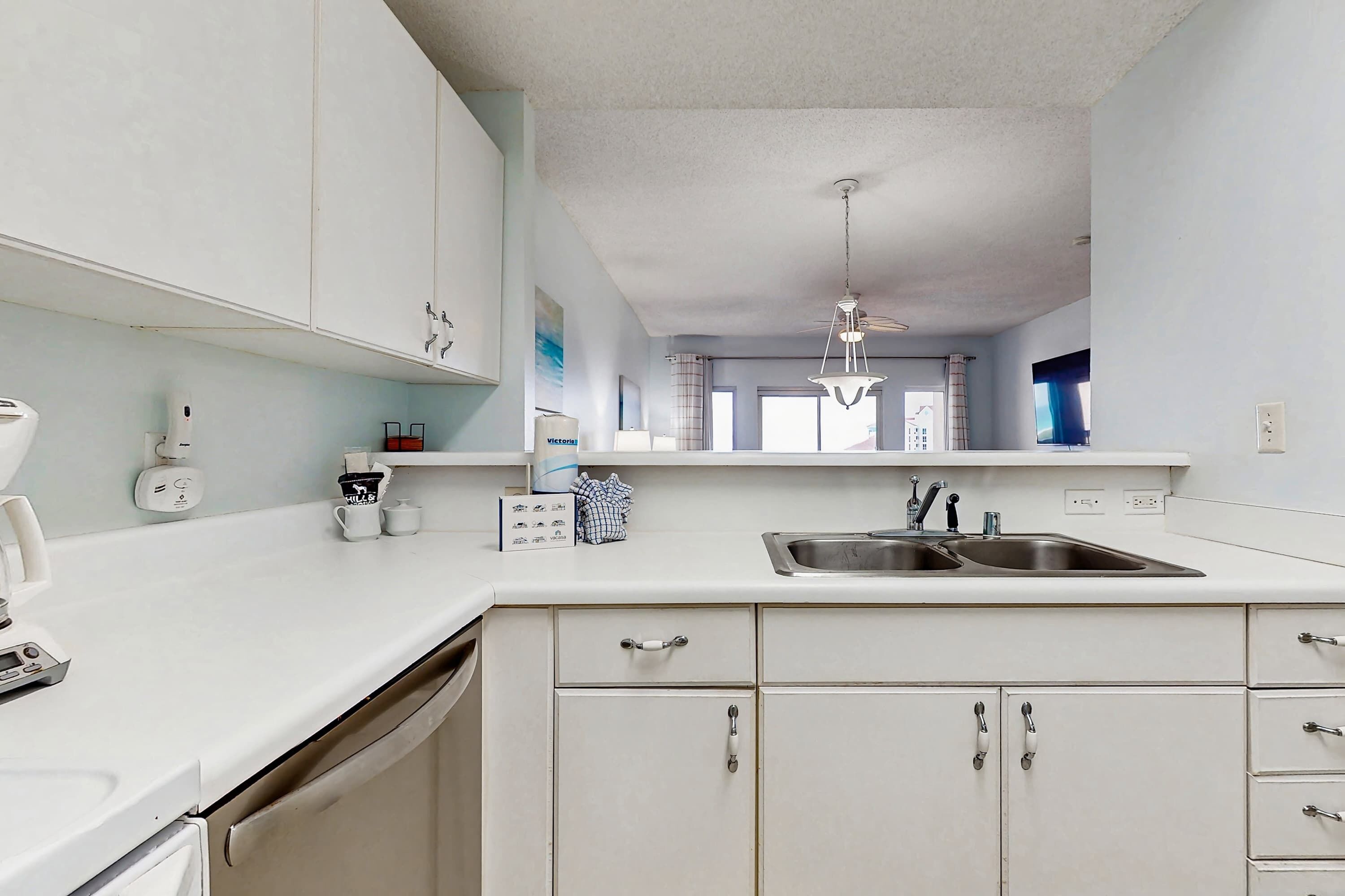 A kitchen with white cabinets, a double sink, and a ceiling fan.