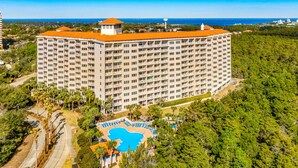 Un hotel grande con varios pisos, una piscina y vistas al océano.