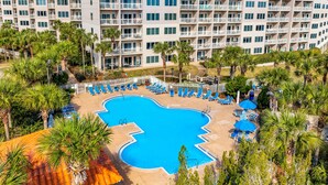 Un resort con una amplia piscina rodeada de tumbonas y palmeras.