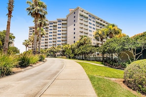 A multi-story hotel with a curved driveway, surrounded by palm trees and well-maintained landscaping. - Exclusive Gulf View, 2BR Balcony (Miramar Beach)