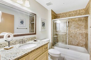 Une salle de bain équipée d’un lavabo, d’un miroir, de toilettes et d’une douche.