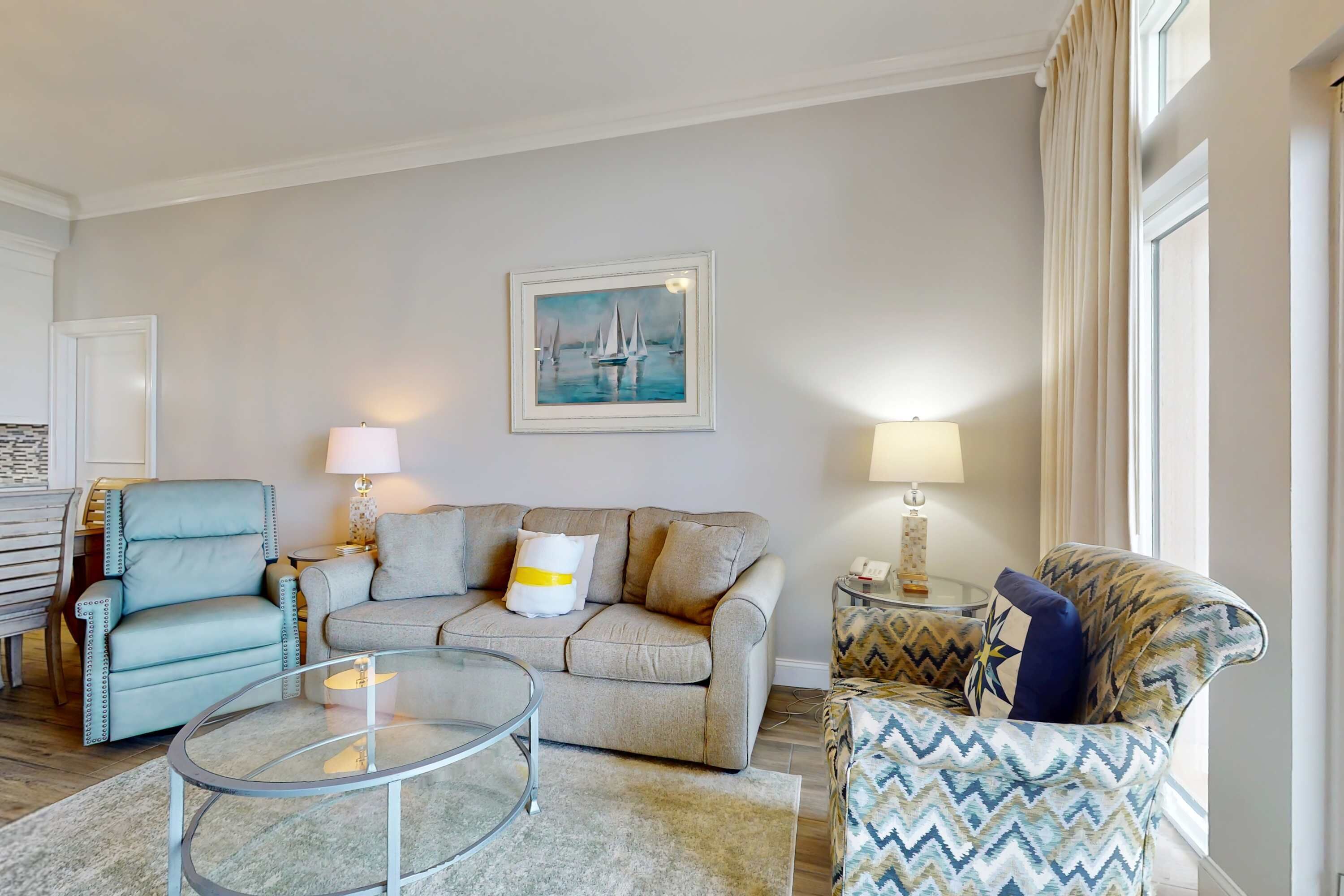 Een woonkamer met een bank, fauteuils, een glazen salontafel en een schilderij aan de muur.
