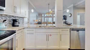 A modern kitchen with white cabinetry, stainless steel appliances, and a central island. - Exclusive Gulf-view penthouse, sleeps 6 (Miramar Beach)