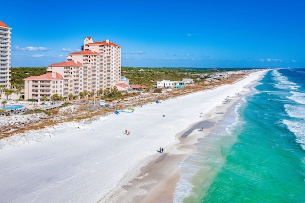 Ein Strandhotel mit mehreren Etagen, einem Pool und Blick auf den Strand.