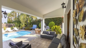 A covered outdoor area with a pool, lounge chairs, a sofa, and a dining table. - Villa Relax, just steps from Latchi beach with a private pool and terraces. (Latchi Beach)