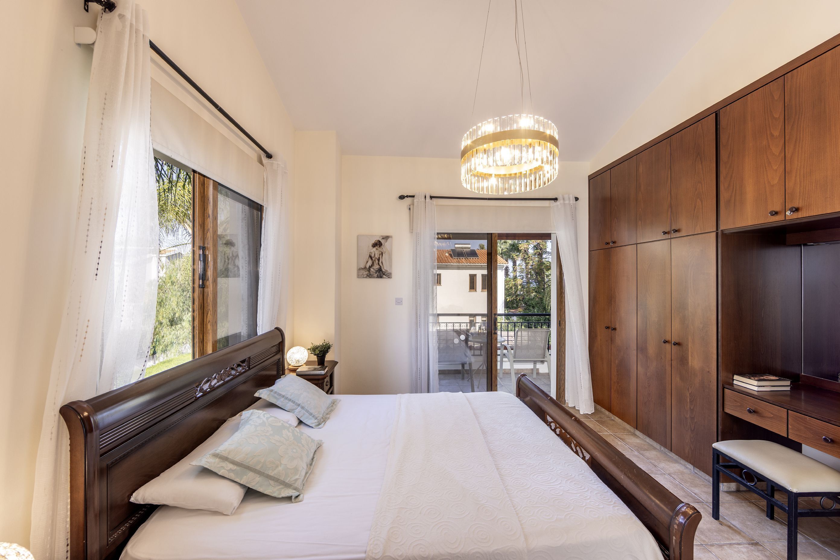 Een slaapkamer met een groot bed, een houten garderobe en een bankje.