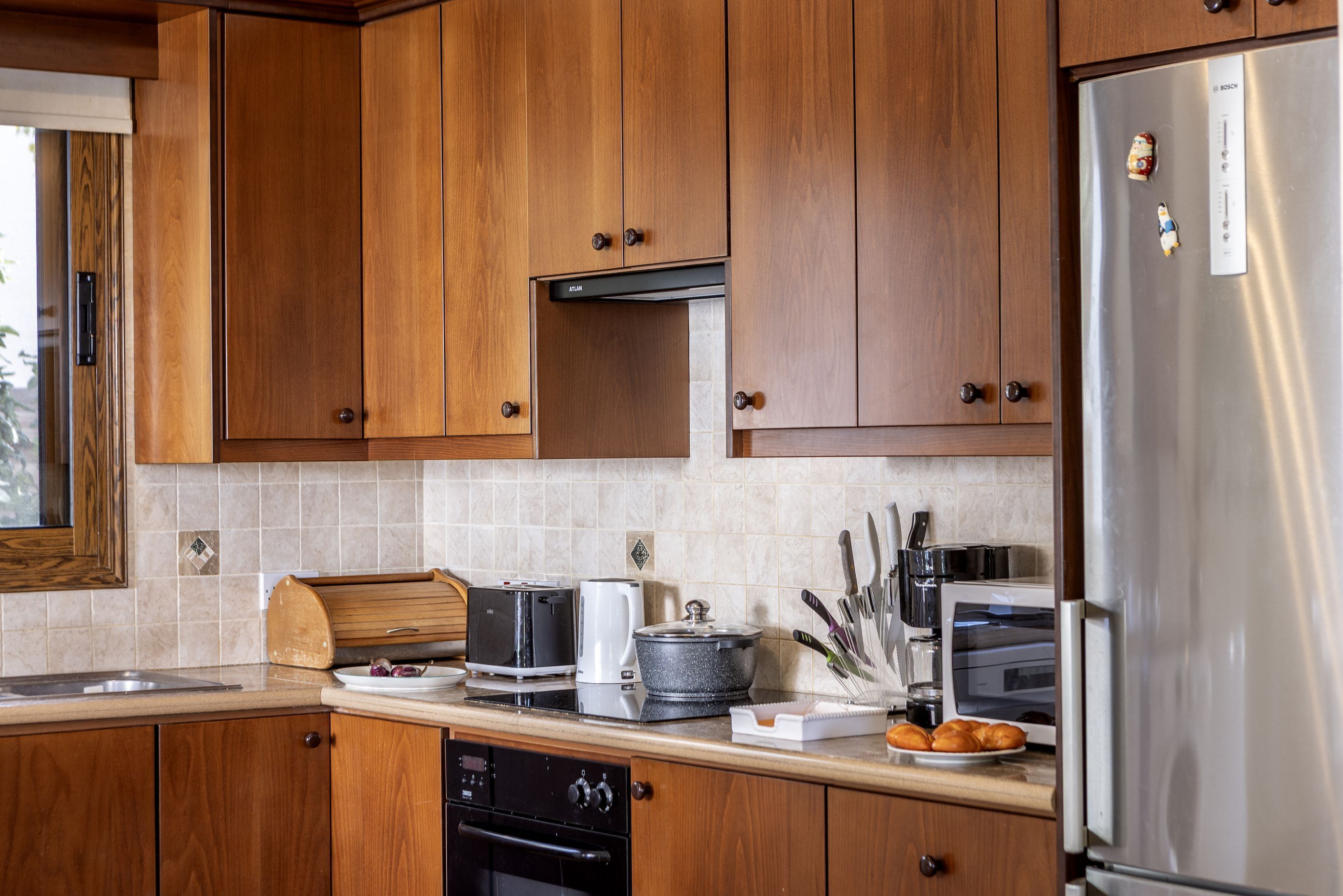 A kitchen with wooden cabinets, a stainless steel refrigerator, a toaster, a coffee maker, and a dishwasher.