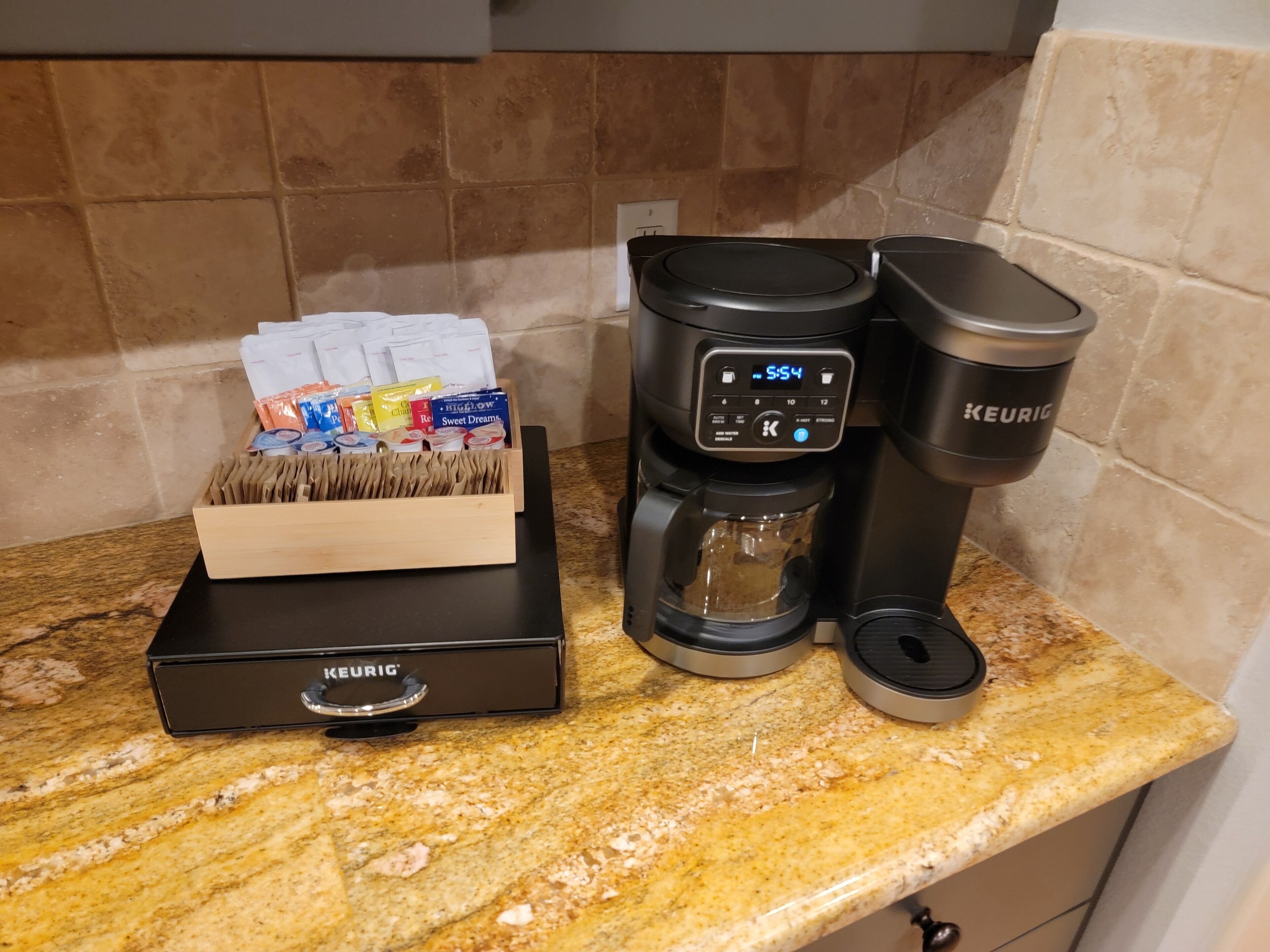 Eine Kaffeemaschine von Keurig auf einer Granitabdeckung mit einem Kaffee-Pod-Halter und einer Keurig-Kaffeetasse.