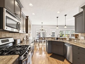 A modern kitchen with stainless steel appliances, dark cabinetry, and a central island. - Family Friendly 4-bedroom Home with Hot Tub Near BSU, Downtown and Airport (Boise)