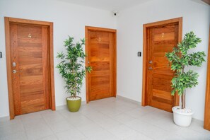 Tres puertas de madera con los números 2, 3 y 4, y dos plantas en macetas.