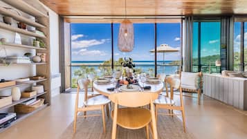 A dining area with a table set for four, overlooking a scenic ocean view.