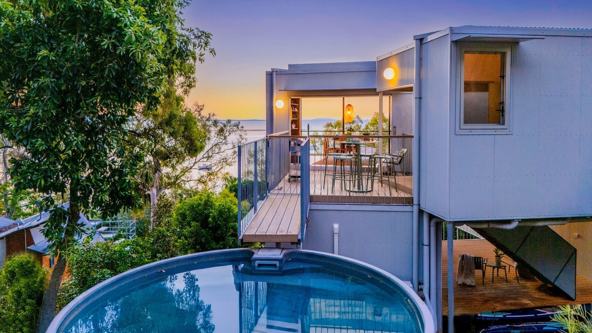 A modern house with a pool, a deck, and a view of the sea.