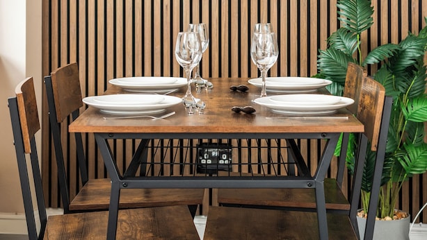 Comedor con una mesa de madera preparada para dos personas, rodeada de sillas.