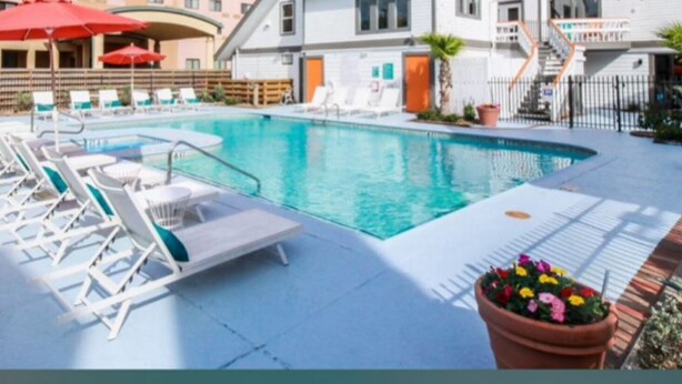 A hotel with a swimming pool, lounge chairs, and a red umbrella. - Modern Studio Apartment Pool & Gym Access Ideal for Relaxing Stays in Houston (Houston)