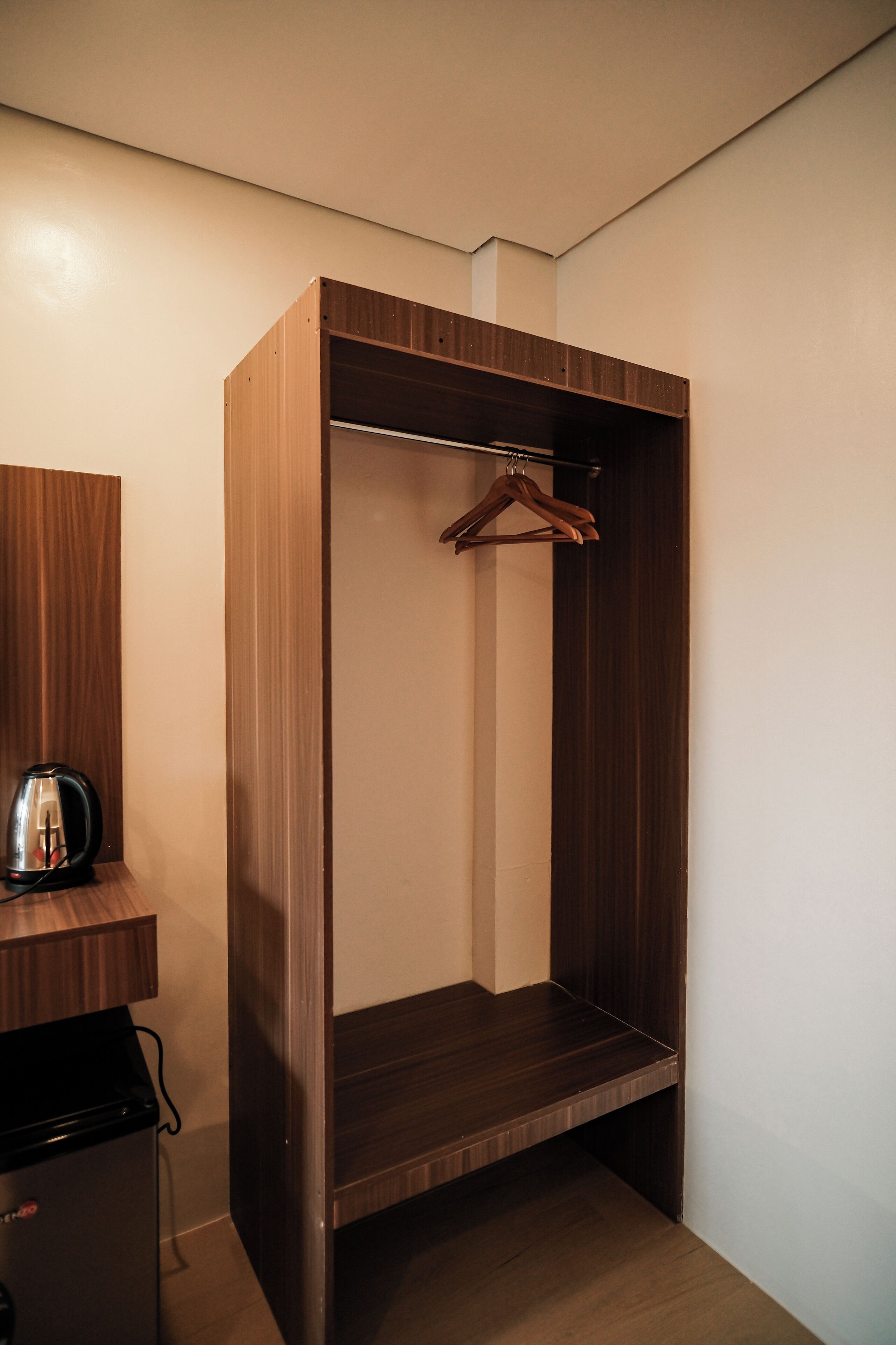 A compact wardrobe with a hanging rod, a small cabinet with a kettle, and a heater.