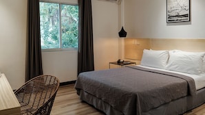 Une chambre d’hôtel moderne équipée d’un lit, d’une chaise, d’un bureau et d’une fenêtre avec des rideaux.