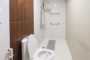 A modern bathroom with a toilet, shower, and handrails. - Hotel Sogo Baclaran (Parañaque)