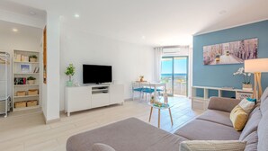 Un soggiorno moderno con divano, televisione e zona pranzo.