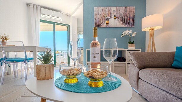 Un soggiorno moderno con divano, tavolo da pranzo con sedie, balcone vista e un quadro appeso al muro.