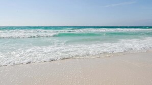 Een strand met helder turquoise water en wit zand.