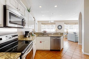 A modern kitchen with stainless steel appliances, white cabinetry, granite countertops, and a central island. - 3BR resort home with private heated pool (Miramar Beach)