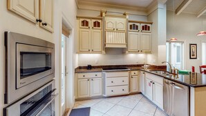 A kitchen with white cabinetry, stainless steel appliances, and a granite countertop. - 3BR villa, steps to beach + Captiva pool (Miramar Beach)