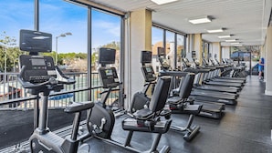 Ein Fitnessraum mit Trainingsgeräten, großen Fenstern und Blick ins Freie.