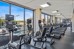 Un gimnasio con equipamiento de ejercicio, ventanas amplias y vistas al exterior.