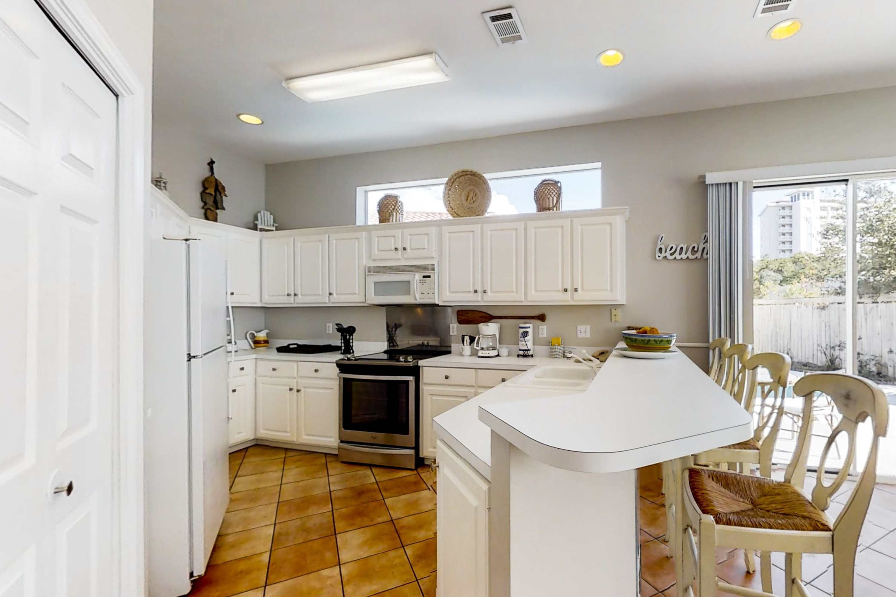 A kitchen with white cabinets, a stove, a microwave, and a dining area with chairs and a table.