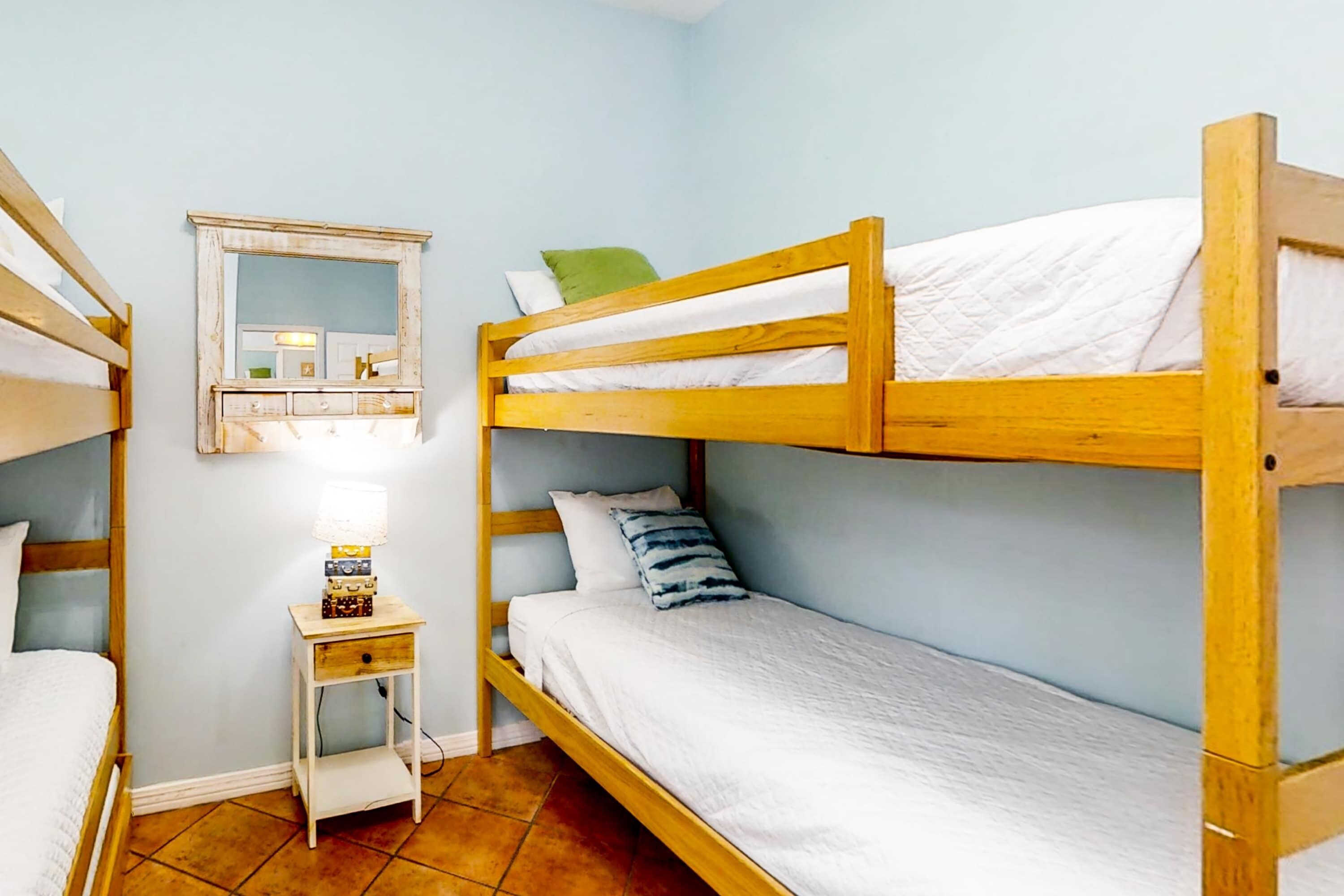 A bunk bed room with a small bedside table and a mirror.