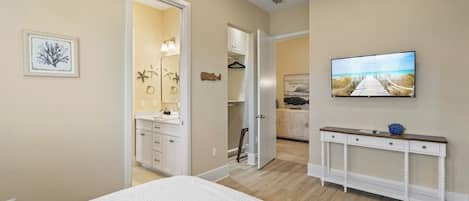 Un dormitorio con cama, televisor, cómoda y vestidor.