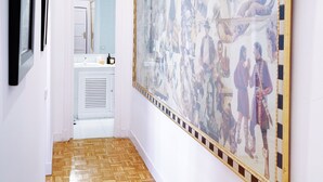 Ein Flur mit einer großen Wandmalerei, Holzboden und einem im Hintergrund sichtbaren Badezimmer.