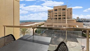 Ein Balkon mit Blick auf Strand und Gebäude.