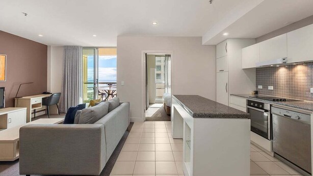 Eine moderne Wohnung mit Wohnbereich, Küchenzeile und einem Balkon mit Blick.