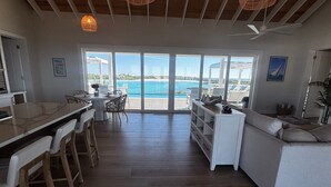 A spacious living area with a large sliding glass door leading to a balcony overlooking a beach.