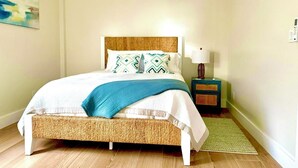 A bedroom with a bed, a bedside table, a lamp, a rug, and a painting on the wall.