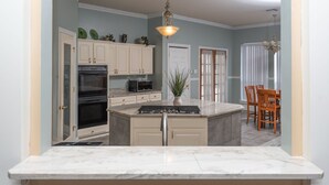 A kitchen with white cabinets, a central island, a stove, and a microwave.