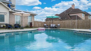A backyard with a swimming pool, outdoor furniture, and a wooden fence.