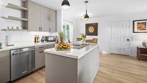 Eine moderne Küche mit einer zentralen Kochinsel, Edelstahlgeräten und Pendelleuchten.
