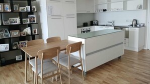 Eine moderne Küche mit einer zentralen Kochinsel, weißen Schränken und einem Essbereich mit Holztisch und -stühlen.