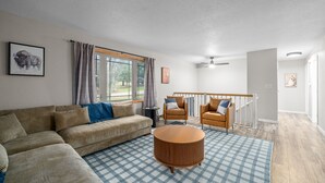 Een woonkamer met een bank, fauteuils, een bijzettafeltje en uitzicht op het buitengebied.
