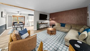 Een moderne woonkamer met een bank, salontafel en een eethoek op de achtergrond.