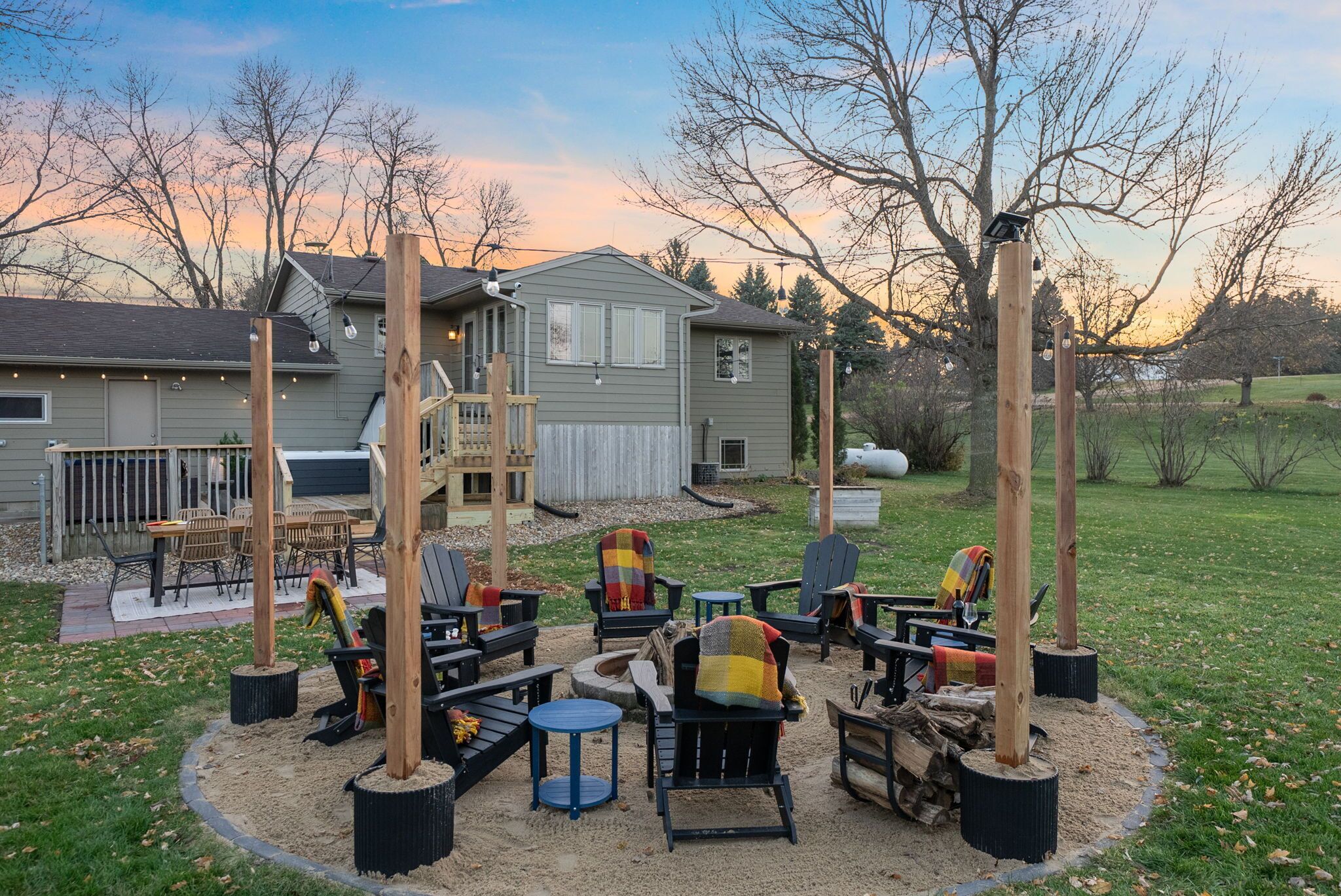 Un espace extérieur aménagé avec plusieurs fauteuils Adirondack et des tables, le tout entouré d’un cercle de sable.
