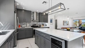 Una cocina moderna con armarios grises, una isla grande y un comedor con vistas.
